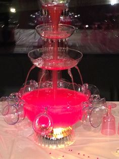 a three tiered water fountain on top of a table with pink liquid in it