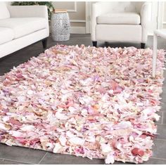 a living room area with a white couch and pink rug on the floor in front of it