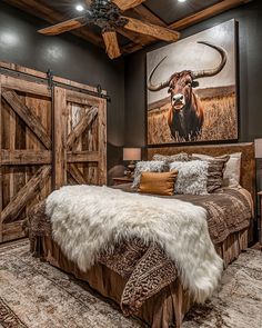 a bedroom with a cow painting on the wall next to a bed and ceiling fan