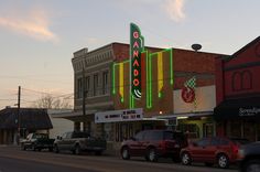 cars are parked on the side of the road in front of an old fashioned casino