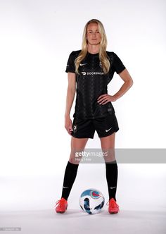 a female soccer player poses for a photo in front of a white background wearing black and red