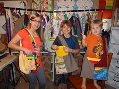 two young children standing next to each other in front of clothes hanging on a rack