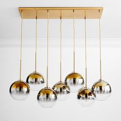 five shiny glass balls hanging from a wooden beam in a white room with gold trim