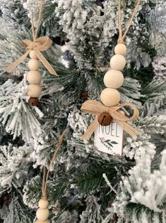 two ornaments hanging from the branches of a christmas tree with snow on it and an old tag