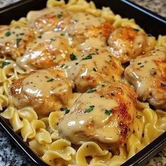 chicken with gravy on top of pasta in a black dish sitting on a granite countertop