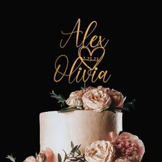 a wedding cake with pink flowers and gold lettering