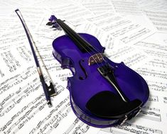 a purple violin sitting on top of sheet music