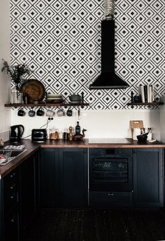 a kitchen with black and white wallpaper, wooden counter tops, and an oven