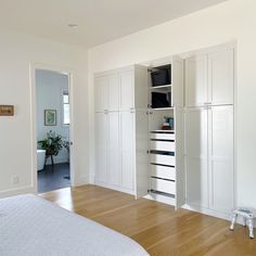 an empty bedroom with white cabinets and wood floors