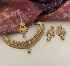 A beautiful 22K goldplated choker set with chandbalis and tika in a regal design to make heads turn! Unfold the euphoria of majestically embossed gold bridal jewelry set in an enticing style that will elevate your look. Details: Choker Necklace Width-1 Inch Choker Necklace Width with Centre Drop-1.75 Inches Earrings Length-2.5 Inches Earrings Width-1.25 Inches Weight of Each Earring-11.5 gms Tika Length-4.75 Inches All products are manufactured using traditional skills from our rich heritage of Pakistan Gold Jewelry, Gold Bridal Sets, Heavy Gold Sets Jewelry Indian Design, Traditional Jewelry Indian, Choker Necklace Indian Gold, Latest Nakshi Jewellery, 3 Tola Gold Set Design, Bridal Gold Jewellery Set, Gold Jewellery Set