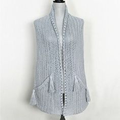 a woman's sweater vest with tassels on the shoulders and back, hanging from a mannequin