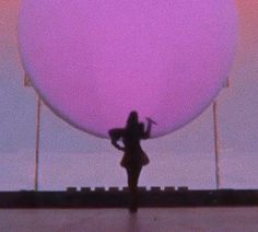 a woman standing in front of a giant balloon with her hands behind her back as if she were dancing