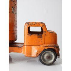 an old orange toy truck sitting on top of a white table next to a can