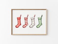 four christmas stockings are hanging on the wall in front of a wooden frame that is hung up