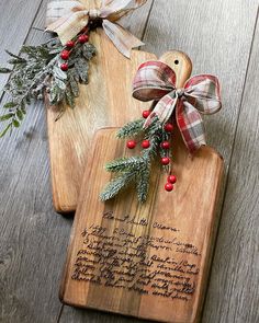 two wooden cutting boards decorated with christmas decorations and writing on them, sitting on a wood floor