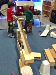 two children playing with wooden toys in a room