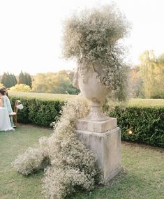 an outdoor wedding ceremony with a sculpture and flowers in the foreground, surrounded by greenery