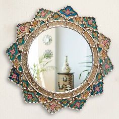 an ornate mirror hanging on the wall above a table with a potted plant in it