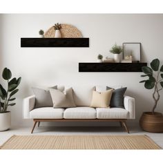 a living room with white couches and potted plants on the shelf above them