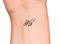 a small tattoo on the wrist of a woman's left arm, depicting a fish