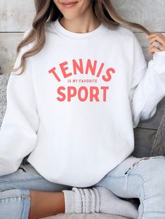 Looking for the ideal gift for the tennis enthusiast in your life? Look no further! Our crewneck is a thoughtful and practical present that will be cherished by anyone who loves to swing a racket. The simple yet bold design proudly declares "Tennis is my Favorite Sport," showcasing your unwavering devotion to the game. Whether you're a seasoned player or just a fan of the sport, this crewneck is sure to become a staple in your wardrobe. Ideal for any situation, a unisex heavy blend crewneck sweatshirt is pure comfort. These garments are made from polyester and cotton. This combination helps designs come out looking fresh and beautiful. The collar is ribbed knit, so it retains its shape even after washing. There are no itchy side seams on these sweaters. White Sportswear Tops For Tennis, Casual White Sweatshirt For Tennis, Casual White Tennis Sweatshirt, White Workout Sweatshirt, Sports White Sweatshirt With Lettering, White Tennis Top Sportswear, White Sports Sweatshirt With Lettering, White Graphic Print Sweatshirt For Workout, Tennis Crew Neck Top With Logo Print