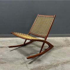 a wooden rocking chair sitting on top of a cement floor next to a gray wall