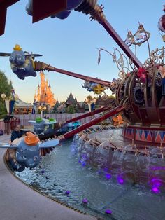 an amusement park ride with many rides and water fountains in the foreground at dusk