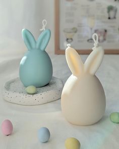 two small plastic easter bunnies sitting next to each other on a white tablecloth