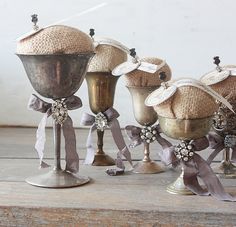 several silver vases with bows on them are sitting on a table next to each other