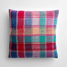 a red, green and blue plaid pillow sitting on top of a white wall