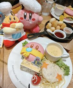 a plate with some food on it and two stuffed animals sitting next to it,