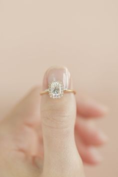 a woman's hand holding an engagement ring with a diamond in the middle and a square shaped center