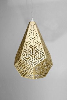 a gold colored light hanging from a white cord with an intricate design on the side