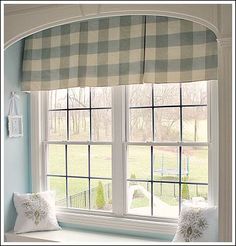 a window with two pillows and a checkered valance