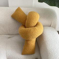 a yellow pillow sitting on top of a white couch next to a potted plant