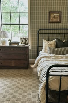 a bed room with a neatly made bed and two night stands next to a window