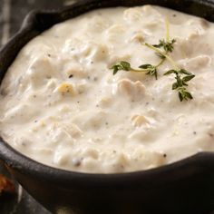 a skillet filled with white sauce and garnished with green sprigs