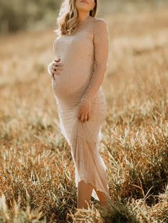 a pregnant woman standing in the middle of a field