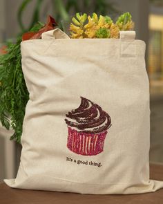 a bag with a cupcake on it sitting on a table next to some plants