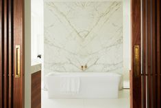 a white bath tub sitting in a bathroom next to a wooden door and wall mounted faucet