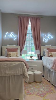 two twin beds in a bedroom with pink curtains and lights on the wall above them