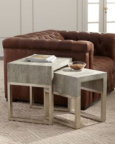 two tables sitting on top of each other in front of a brown couch and chair