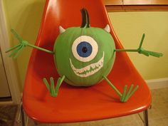 a green monster sitting on top of a red chair