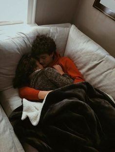 two people are sleeping on a couch together