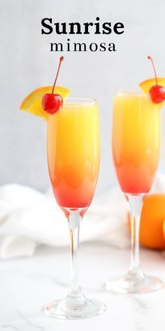 two glasses filled with orange juice and topped with a cherries garnish on the rim