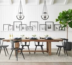 a dining room table with chairs and pictures on the wall above it, along with a potted plant