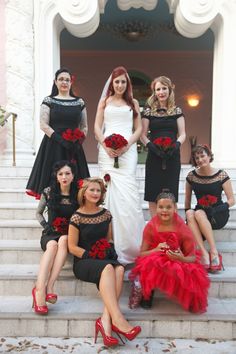 a group of women dressed in black and red posing for a photo on some steps