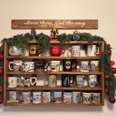 a wooden shelf filled with lots of coffee mugs and christmas decorations on top of it