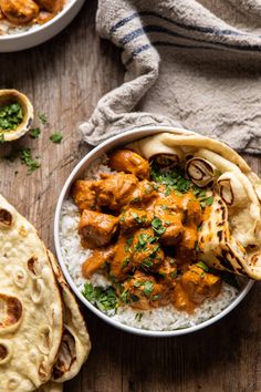 a bowl filled with chicken and rice next to pita bread on top of a wooden table