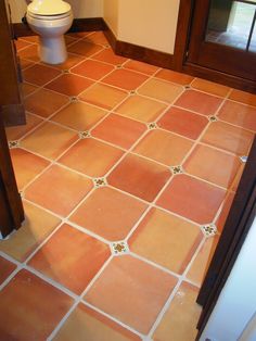 a bathroom with a toilet and tile flooring in the middle of it's room